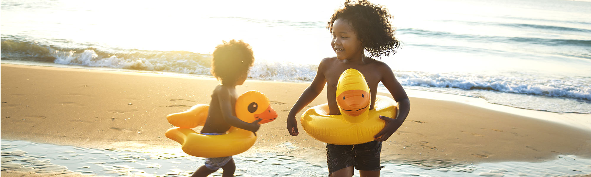 children playing on beach wearing inner tube duckies