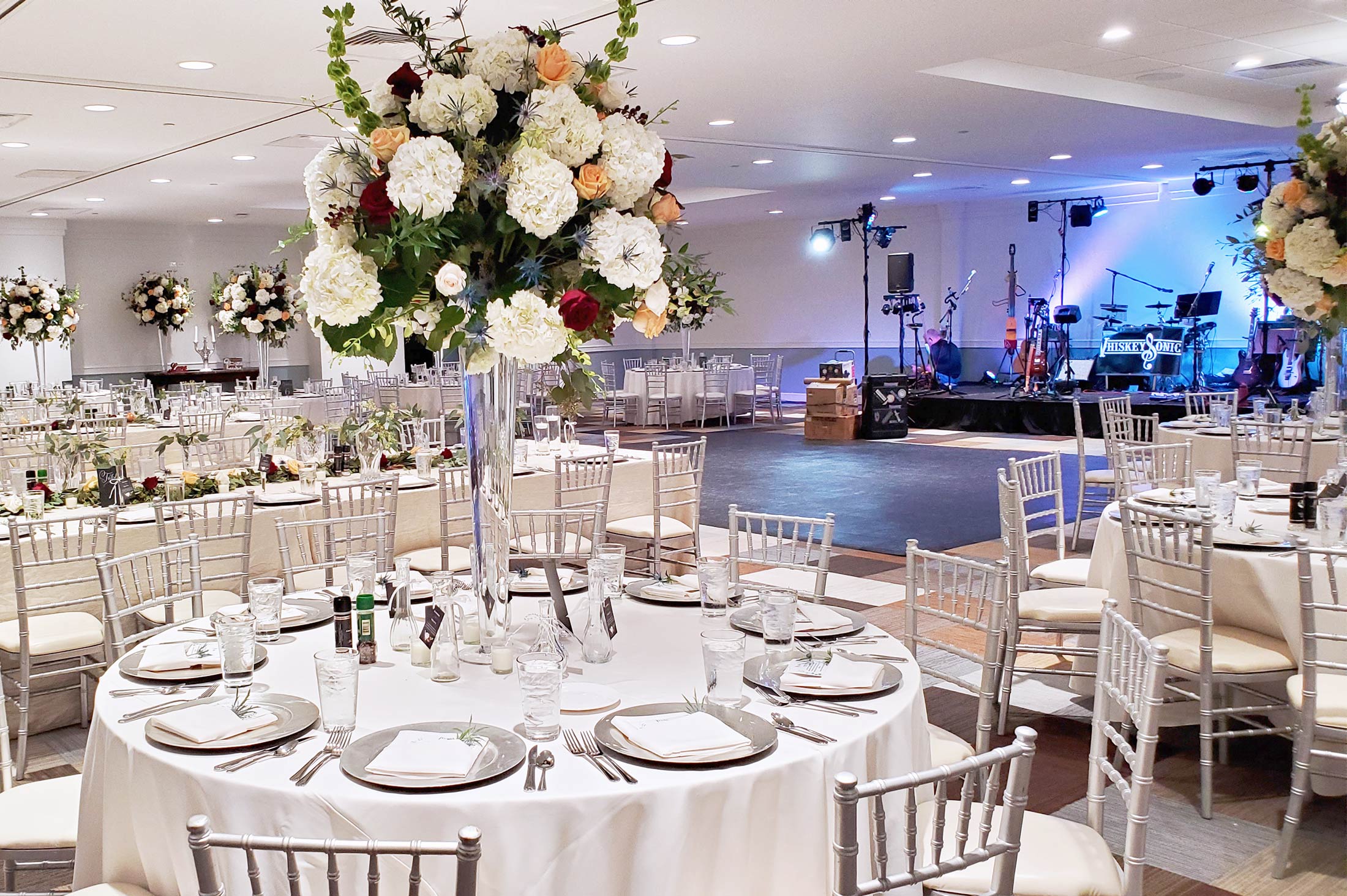 reception in ballroom with tall floral arrangements on tables