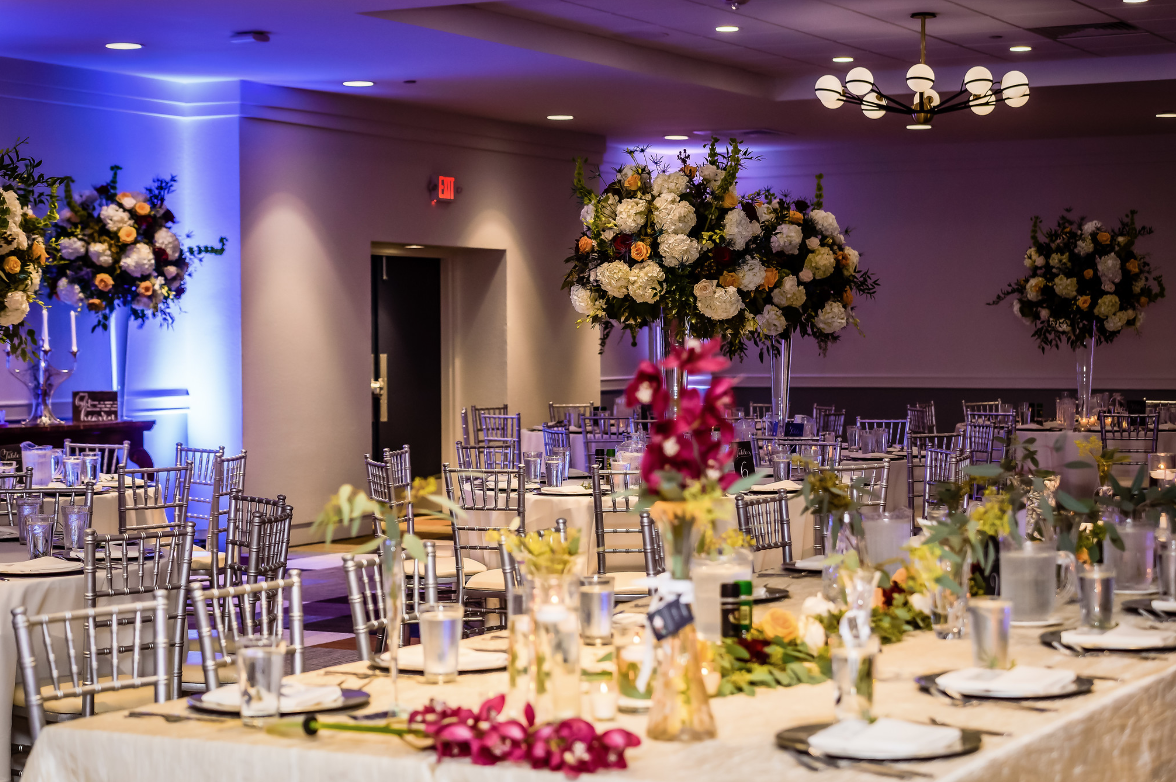place settings and floral arrangements on long reception table and banquet rounds